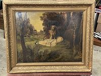 Full view of oil painting in ornate gilt frame leaning against background