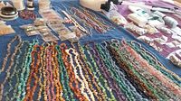 Wide view of bead strands, wire spools, glue bottles, findings, lamp and pliers on blue towel