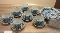 Set of 5 cups and matching saucers with Blue Onion pattern, showing detailed blue floral designs on white porcelain.