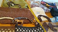 Overview of various handcrafted handbags showing crochet, woven, and mesh textures with different handle styles, zipper closures, and decorative elements.
