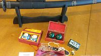 Full view of the six oriental items showing the samurai sword laid horizontally behind various small boxes and figurines on a wooden table
