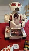 RAD 2.0 robot figure showing front with red eye panels, chest sensors, and track base on red fabric.