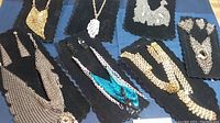 Overview of all 7 jewelry pieces displayed on black fabric including gold and silver tone mesh necklaces and earrings.