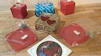Various glass and crystal art pieces including boxed clear crystal cubes, red glass items wrapped in plastic, and a circular glass stained glass style panel.