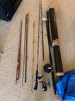 Five fishing rods with attached reels and a black rod storage tube