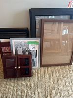 Several varied picture frames including silver metal, black and brown wood frames, and a small wooden display case with hinged doors