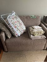 Full view of brown sofa bed with bedding stacked on seat