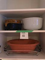 Bowls and clay roasting pot displayed on shelves showing different angles.
