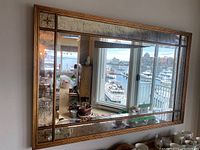 Front view of large rectangular mirror reflecting living room and harbor scene