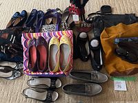 Overview of assorted women's shoes, handbags, and handbags on carpeted floor