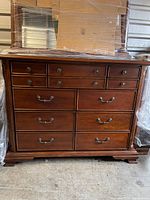 Front view of nine-drawer dresser base with antique brass-tone handles in cherry finish