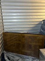 Two rectangular table leaves with burled ash veneer top, standing upright in storage unit