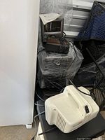 Two stacked box TVs visible including a Sharp 13K-M100, wires and cables tangled around. White air purifier visible at the front with on/off switch.
