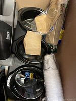 Shark cordless hand vacuum with charging base, three black Farberware crock warmer bowls, plastic cups and stir sticks
