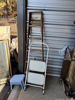 Full view of the 5-foot wood ladder, white metal step stool, and gray plastic step stool leaning against a wall.