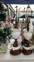 Photo showing the pair of hobnail milk glass lamps with wooden bases alongside the floral arrangement.
