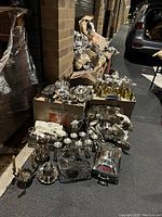 Wide shot of the full lot arranged outdoors showing many items stacked on boxes and ground including glasses, bowls, trays, and pitchers.