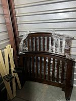 Two dark wood twin bedframe headboards and footboards wrapped in plastic film.