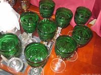 View of 10 green crystal glasses grouped together showing their pattern and clear stems.
