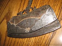 Photo of antique flint lighter showcasing metal and leather construction with embossed metal decorative patterns and attached leather strap.