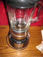 Front view of the blender showing glass pitcher, handle and the stainless steel base with control buttons.