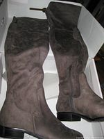 Photo showing both boots lying in original box, displaying their brown soft leather material and flat heel.