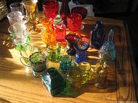 Top-down view of assorted small colored glass items arranged on a wood surface illuminated by sunlight