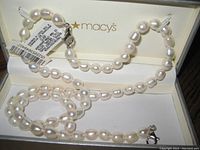 Open gray Macy’s jewelry box with necklace and bracelet coiled inside