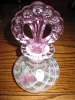 Front view of the Fenton perfume bottle showing pink floral glass stopper, lattice pattern with hand painted flowers, and Fenton sticker on body.