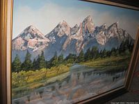 Photo showing the signed oil painting of mountain range with reflection in water, framed and in good condition.