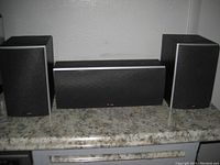Front view of the three Polk Audio speakers, two bookshelf speakers and one center speaker with black grills.