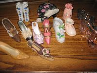 Photo showing assortment of porcelain miniature shoes and two small bags in various colors and detailing, laid out on wooden surface.