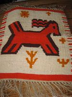Full view of flax tapestry showing stylized horse image with fringe edges, primarily red, black, and orange on white background.