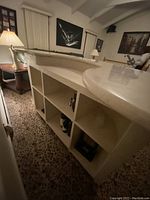 Side view showing the marble countertop and open cubby storage shelves underneath the bar back.