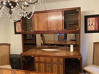 Front view of the wooden dining room cabinet showing two glass-paneled upper doors, mirrored back in the middle section, three drawers, and two lower wood doors