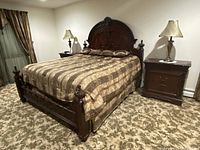 Photo of the footboard attached to a bed with matching bedding and flanked by nightstands, showing its style and condition in a bedroom setting.