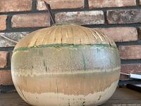 Single pottery vase with green, beige, and brown glaze and a textured rim design.