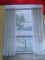 Photo of the drapery panels hanging over a window, showing fabric color and metal grommets.