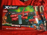 Front view of the product packaging showing the Omega and Extinct blasters set with branding and dinosaur graphics.