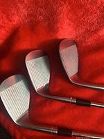 Close-up of putter heads showing grooved faces, chrome finish, and standard golf putter shape.