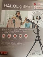 Front of boxed Halo Light Pro showing brand, product name, and product image with woman using ring light, tripod, phone mount and microphone.