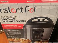 Photo of the front box of Instant Pot Duo Gourmet multi-use pressure cooker, showing branding, model, and key features.