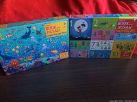 Set of children's jigsaw puzzles displayed on red fabric surface. Box shows colorful underwater sea creatures and puzzle details.