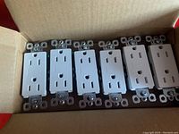 Box containing 30 white electrical outlets in new condition.