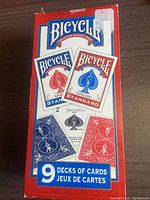 Photo showing the box containing 9 decks of Bicycle Standard playing cards, with red and blue backs visible.