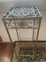 Full view of the iron stand showing its height and square top with scrollwork.