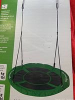 Photo of the round platform swing showing the green and black seat hung by ropes.