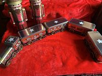 Full view of the vintage tin toy train with four connected cars on a red cloth background