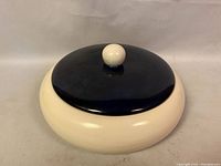 Front-top angled view showing the cream-colored rounded ceramic jar with dark blue lid and round knob handle.