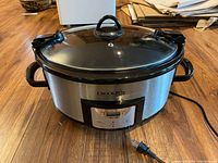 Front view of vintage Crock-Pot slow cooker showing stainless steel finish, black handles and control panel with power cord.